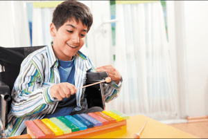 Young boy in wheelchair playing xylophone
